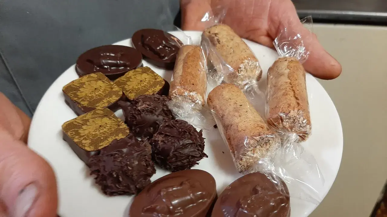 Assortiment de chocolats et biscuits, dont une spécialité d'Alençon, présentés sur une assiette blanche.