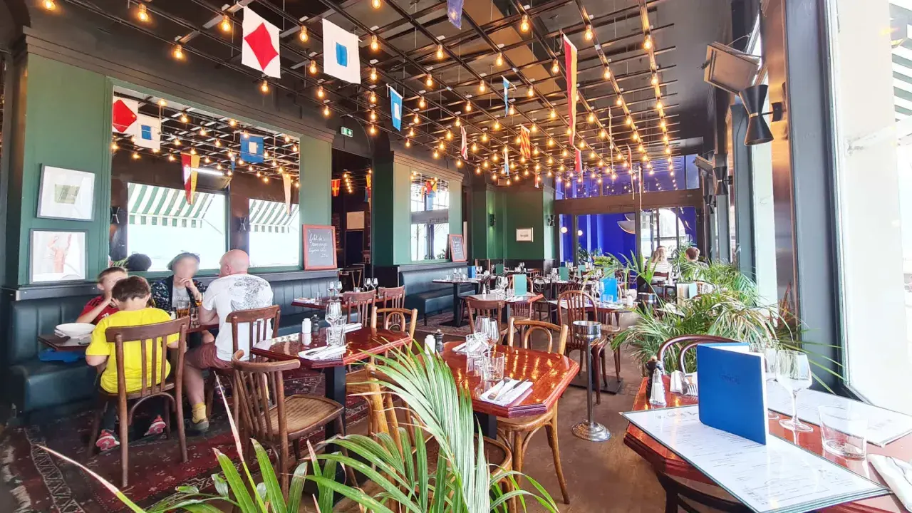 Ambiance marine dans un des restaurants de Saint-Malo. Drapeaux nautiques, lumières tamisées et tables dressées pour un repas convivial.