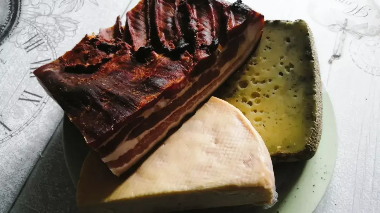 Un plateau de spécialités des Vosges : un morceau de lard fumé et deux fromages, l'un à pâte dure et l'autre plus crémeux.