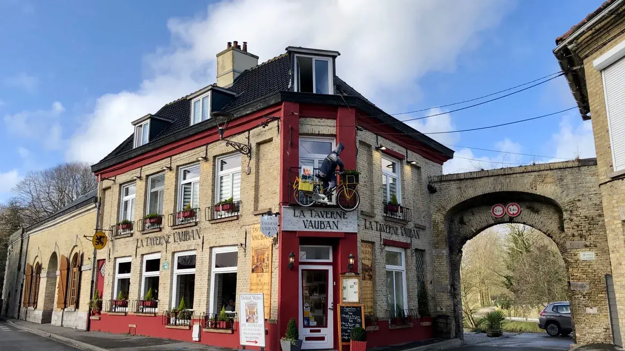 Façade de la Taverne Vauban à Bergues, avec une enseigne et une décoration de cycliste.