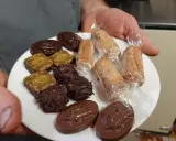Assortiment de chocolats et biscuits, dont une spécialité d'Alençon, présentés sur une assiette blanche.