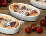 Deux clafoutis aux cerises, une spécialité auvergnate sucrée, saupoudrés de sucre glace, avec des cerises fraîches sur le côté.