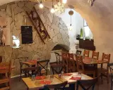 Ambiance chaleureuse dans un des restaurants de Briançon. Murs en pierre, tables en bois, tableau de menu et décoration hivernale.