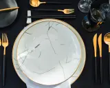 Une table dressée avec élégance, évoquant une ancienne tradition française. Vaisselle moderne aux accents dorés, prête pour un repas raffiné.