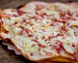 Tarte flambée gourmande, spécialité d'un restaurant alsacien à Nantes. Crème, lardons et oignons sur une pâte fine et croustillante.