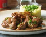 Une assiette de fricassée de rognons de veau, tendres et savoureux, accompagnés d'une purée de pommes de terre onctueuse et garnie de persil frais.
