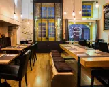 Ambiance chaleureuse au restaurant "Les Fougeres". Tables en bois brut, banquette en cuir et cheminée imposante créent un décor rustique et élégant.