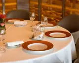 Dressage table gastronomique élégant avec vaisselle raffinée, verres à vin et une petite composition florale.