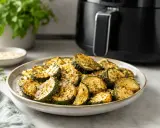 Courgettes croustillantes et dorées, fraîchement sorties de l'air fryer, saupoudrées d'herbes. Un délice sain et rapide.