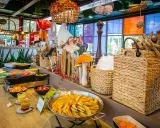 Buffet coloré avec des plats de courges, salades et fruits. Décoration ludique avec des champignons et un personnage de conte de fées, dans l'ambiance du resto Futuroscope.