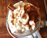 Un déliceux café liégeois glace, couronné de chantilly, saupoudré de cacao et orné d'un bâton de cannelle.