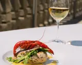 Un plat de poisson avec une écrevisse rouge, roquette et sauce, accompagné d'un verre de chenin blanc sec ou moelleux.