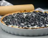 Tarte aux myrtilles traditionnelle, garnie de fruits frais et d'une crème onctueuse, prête à être dégustée.