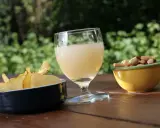 Verre de boisson claire, chips croustillantes et mélange de fruits secs, une spécialité PACA pour un apéritif ensoleillé.