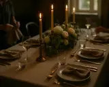 Un dîner aux chandelles, un bouquet floral et des couverts dorés évoquent l'art de la table à la française.