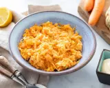 Un bol de carottes râpées originales, avec un quartier de citron et une coupelle de mayonnaise à côté.