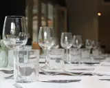 Un verre à eau et un verre à vin sont positionnés sur une table dressée, prêts pour un repas.