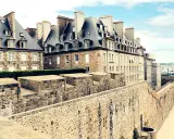 Murs de pierre de la ville fortifiée de Saint-Malo, avec des maisons bretonnes typiques et une vue sur la mer. Imaginez une pause à la taverne de Saint-Malo.