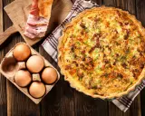 Quiche Lorraine, un classique de la gastronomie lorraine, avec ses ingrédients frais : œufs, lardons et herbes.