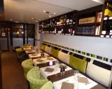 Tables dressées dans un restaurant à Aurillac, idéal pour un repas du dimanche. Les étagères débordent de bouteilles de vin.