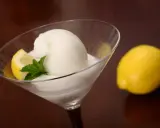 Glace colonel rafraîchissante dans un verre à martini, garnie d'une tranche de citron et de menthe. Un citron entier est posé à côté.