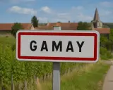 Panneau d'entrée du village de Gamay, au cœur de la région viticole. Vignes et clocher en arrière-plan.
