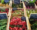 Un étal de marché débordant de légumes frais, offrant un aperçu des spécialités de Bretagne : radis, fèves, rhubarbe, navets, betteraves et choux rave.