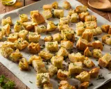 Des morceaux de pain grillés, parsemés d'herbes, prêts à garnir une salade. Ces croutons maison sont un délice croustillant.
