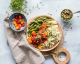 Un délicieux repas parisien : saumon grillé, haricots verts, riz et tomates cerises, accompagné de pesto et de pousses fraîches.