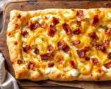 Flammekueche gourmande avec sa crème onctueuse, oignons caramélisés et lardons croustillants. Une recette facile pour un plaisir garanti.