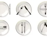 Six assiettes blanches avec des couverts disposés de différentes manières, illustrant la position des couverts signification.
