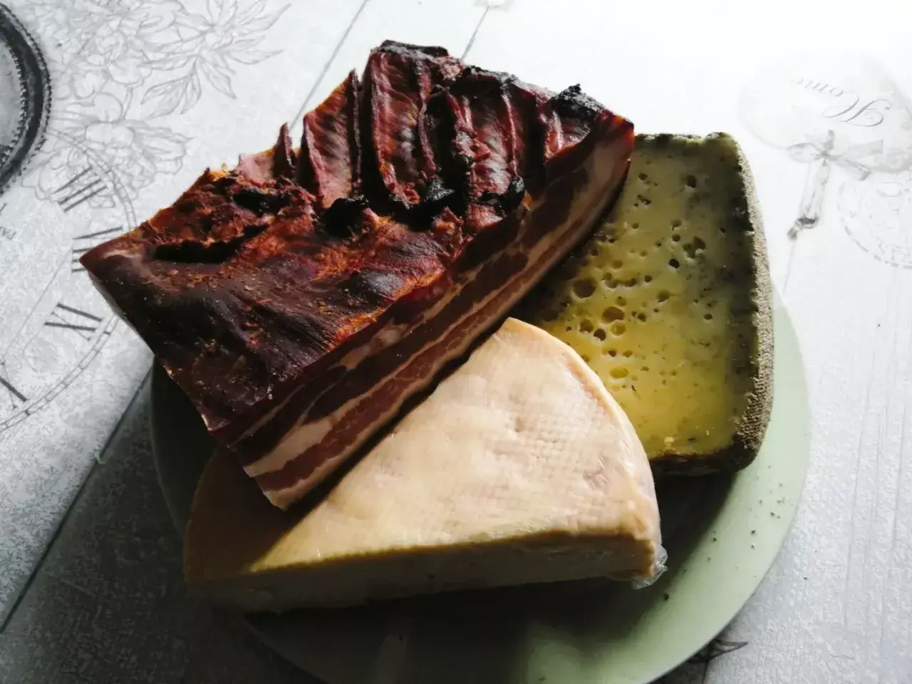Un plateau de spécialités des Vosges : un morceau de lard fumé et deux fromages, l'un à pâte dure et l'autre plus crémeux.