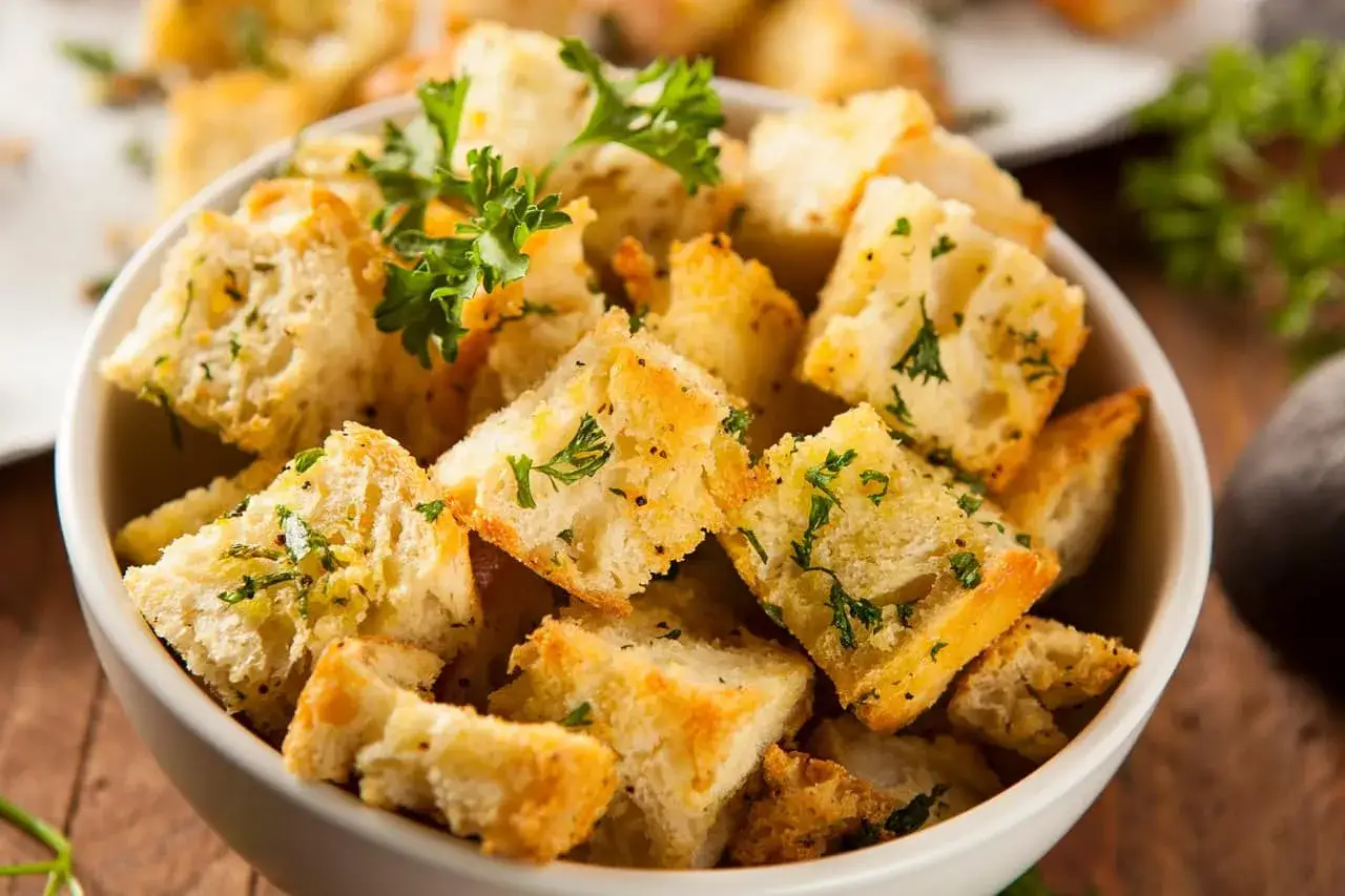 Un bol rempli de croutons dorés et croustillants, parsemés de persil frais. Parfaits pour ajouter du croquant à vos salades.