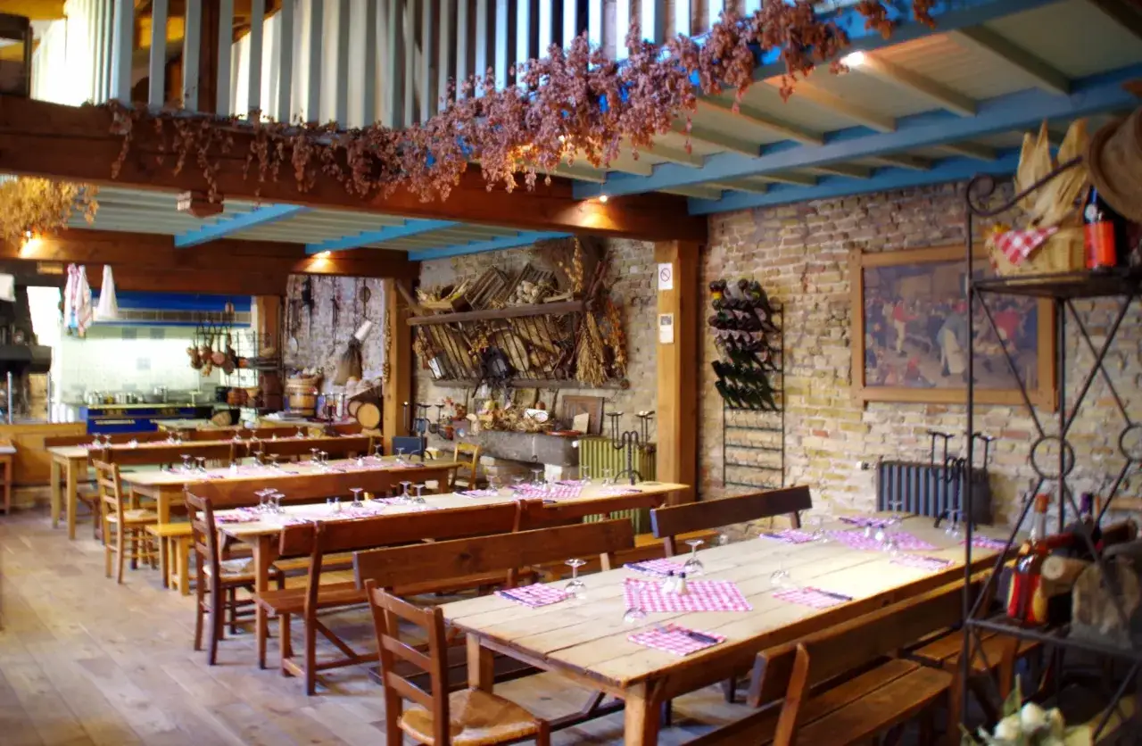 Ambiance rustique à la taverne Vauban. Tables dressées avec des nappes à carreaux roses, prêtes à accueillir les convives pour découvrir le menu.