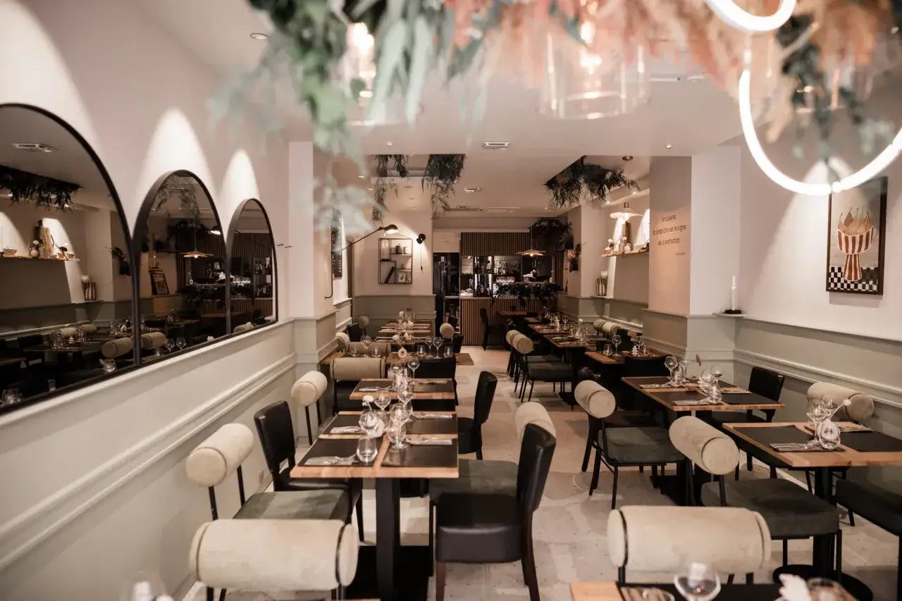Ambiance chic dans ce restaurant Letz, tables dressées, miroirs élégants et végétation suspendue créent un cadre invitant.