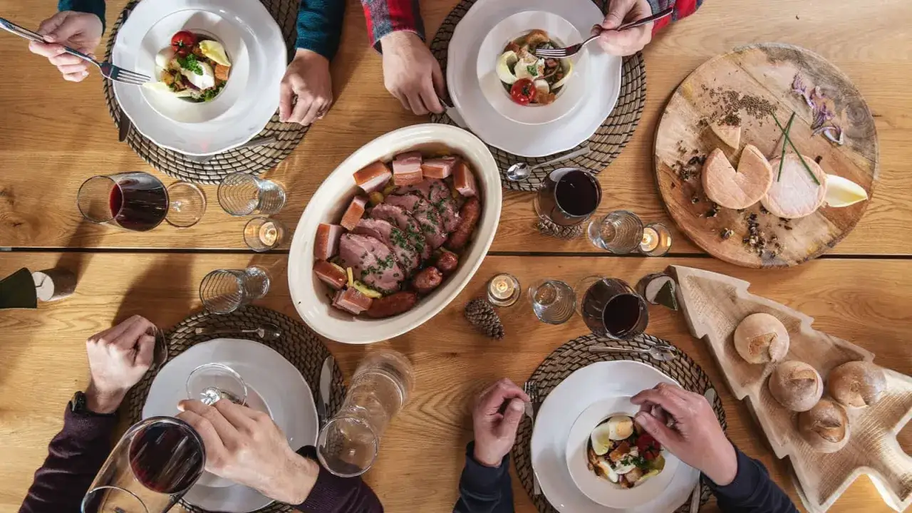 Un repas convivial autour de spécialités des Vosges : rôti, saucisses, fromage et pain.