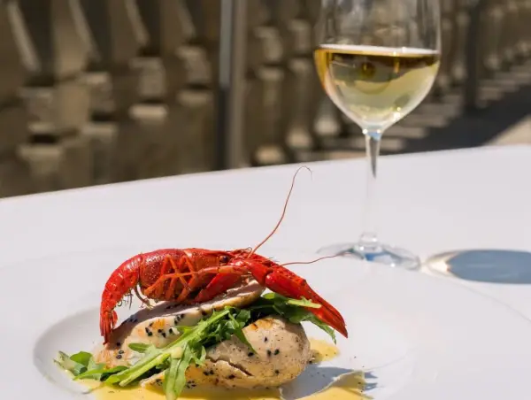 Un plat de poisson avec une écrevisse rouge, roquette et sauce, accompagné d'un verre de chenin blanc sec ou moelleux.