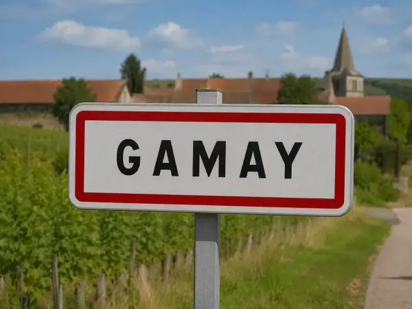 Panneau d'entrée du village de Gamay, au cœur de la région viticole. Vignes et clocher en arrière-plan.